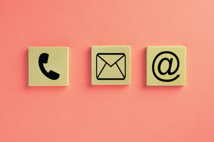 Three wooden tiles each with an image of a phone, letter, and @ symbol