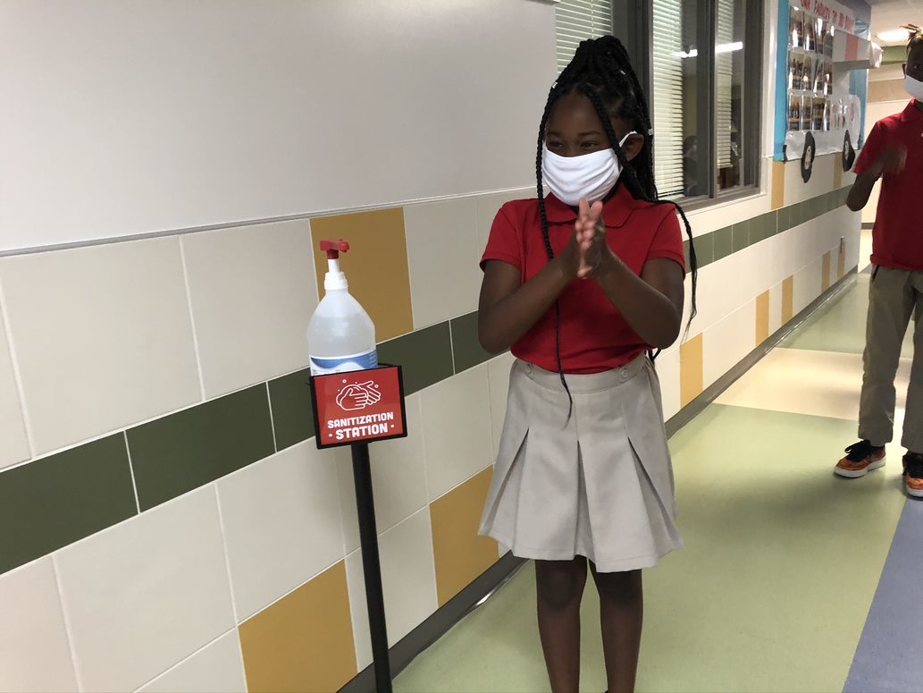 school girl sanitizing hands