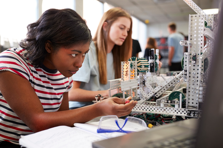 Two female students working on technical machinery in a STEM lab