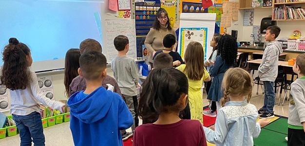 Teacher and students in classroom with easel and whiteboard