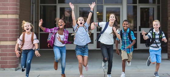 students in front of school jumping