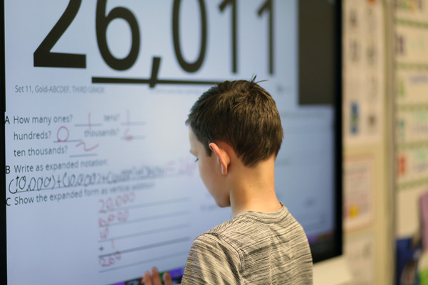 boy at digital whiteboard with math equation