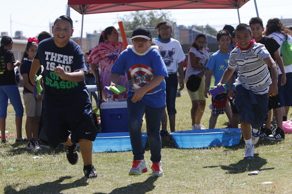 kids racing outdoors at a field day event, tent in background