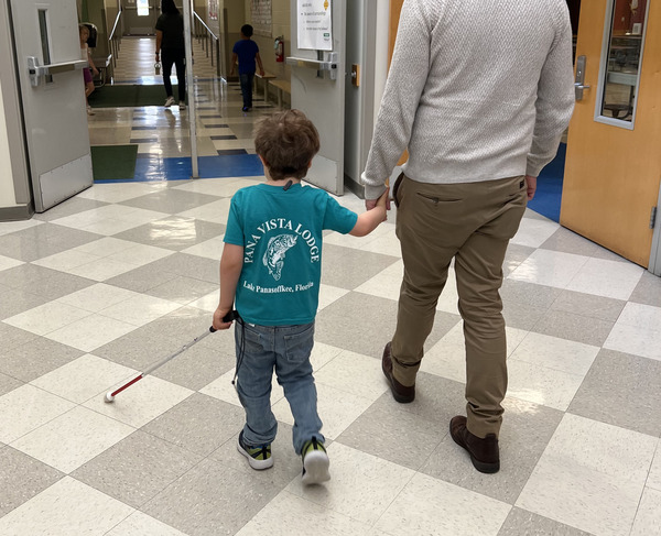 student with cane walking with teacher 