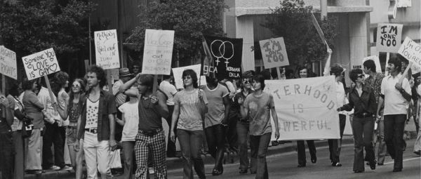 People wearing 1970s-style clothing march in a gay Pride parade