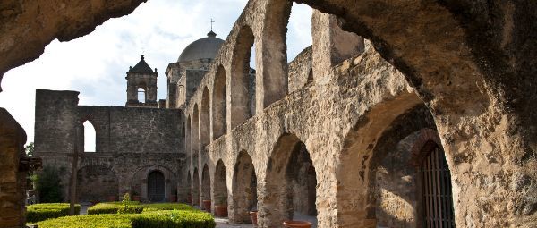 Stone Spanish mission viewed through the arch of a cloister