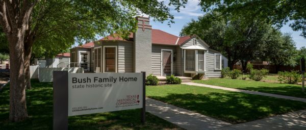 Gray clapboard home with a sign in front reading ?Bush Family Home State Historic Site, Texas Historical Commission?