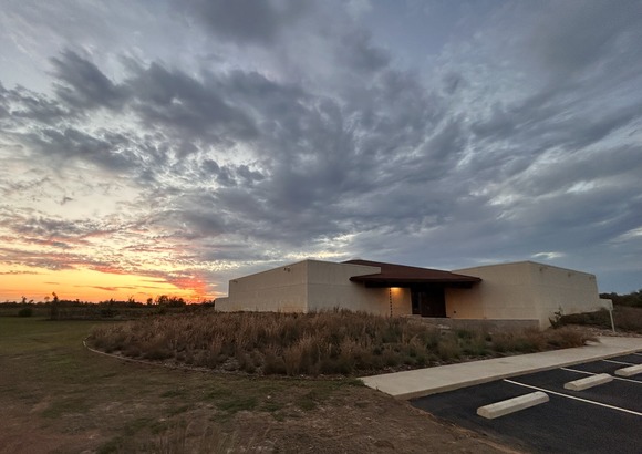 Sunset over building in field