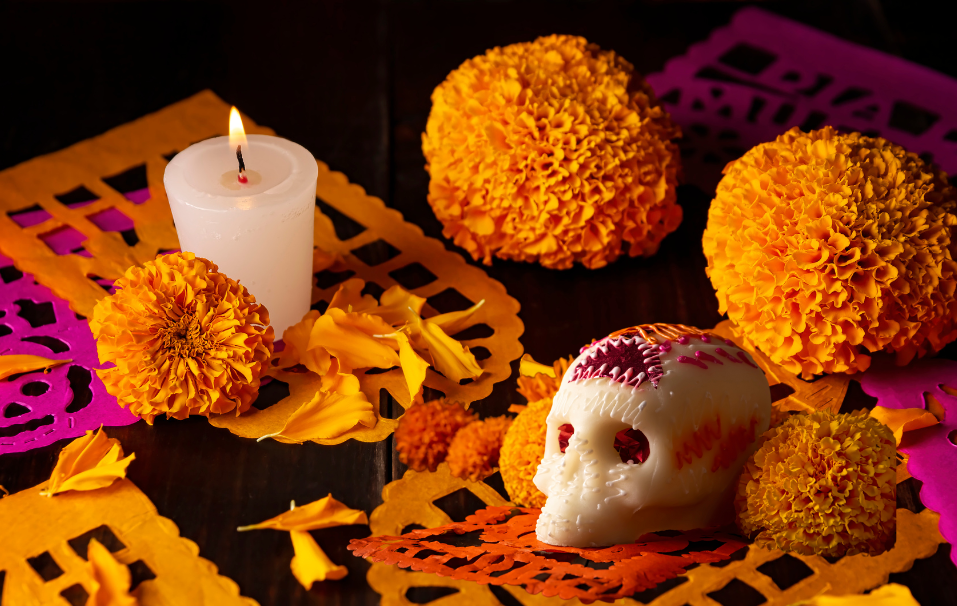 A tablescape of orange flowers, a skull, and lit candle