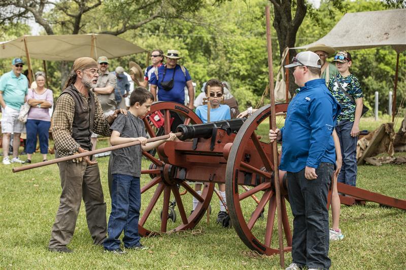 Boy loads cannon at historical reenactment 