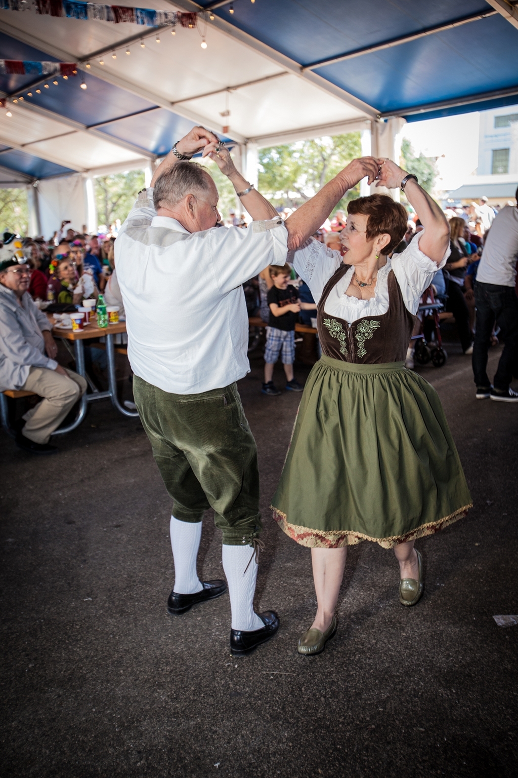Man and woman dancing at festival in green attire 