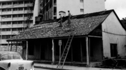 black and white photo of men on top of old house