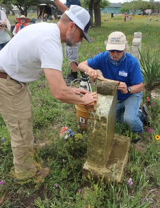 Two men cleaning a historic gravestone