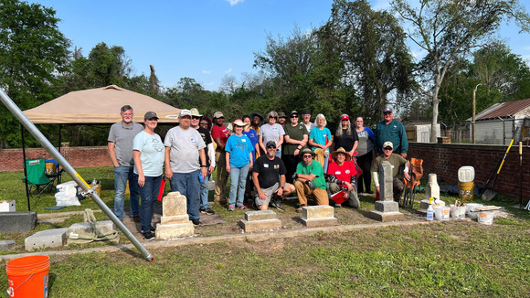 Workshop participants stand beside newly-repaired historic gravestones 