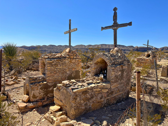 Color photo of traditional Mexican headstones built of rock and wooden crosses in Terlingua, Texas