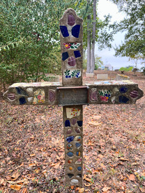 Color photo of a traditional Mexican cross made of concrete and colorful blue and white tile at the Elgin Mexican Cemetery.
