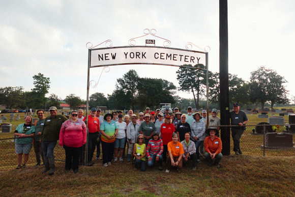 Color photo of group photo taken in front of the New York Cemetery historic archway in East Texas