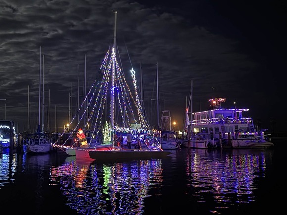 A boat in a marina at night with Christmas lights 