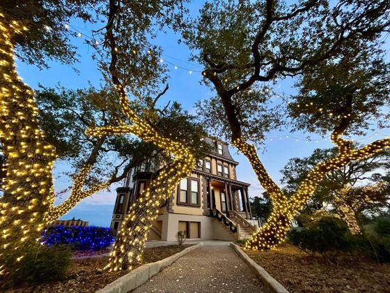 Victorian mansion surrounded by christmas light trees