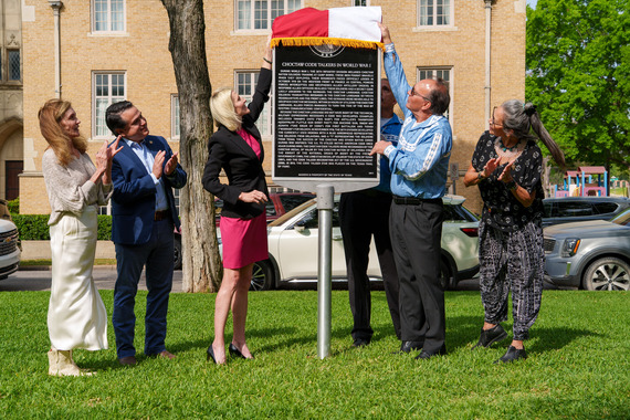 Five people stand on a lawn during a daytime ceremony, unveiling a historical marker titled "Choctaw Code Talkers in World War I."