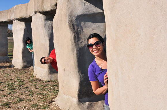 3 people peaking their heads out from behind large rocks 