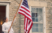 Woman in period clothing holding American flag