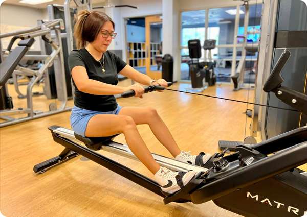 Image of a young woman exercising on a row machine at a Waco community center wellness center.