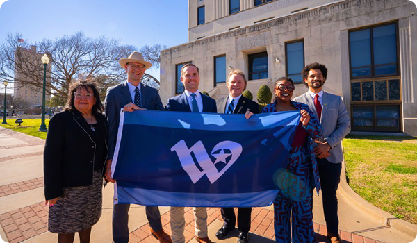 Waco City Council members in front of City Hall holding the new City of Waco flag.