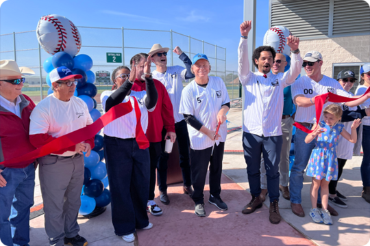 Waco City Council cheering after cutting the ceremonial red ribbon in front of a ballpark.