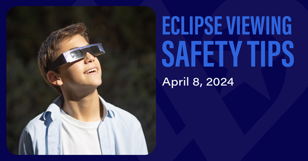 Young boy wearing eclipse safety glasses looking up at the sky.