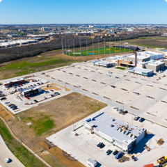 Aerial view of Cinemark, Top Golf, other buildings, and a mostly empty parking lot