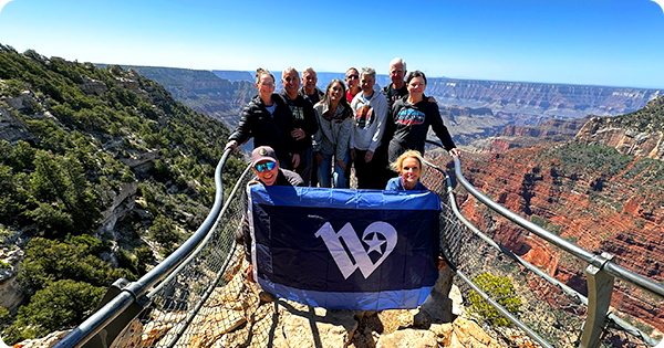 Group of people holding the City of Waco flag overlooking the Grand Canyon