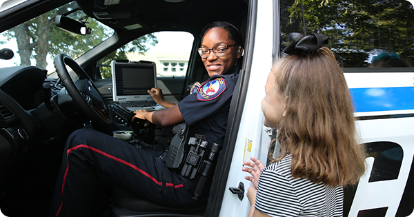 A female police officer in a police car interacting with a young girl