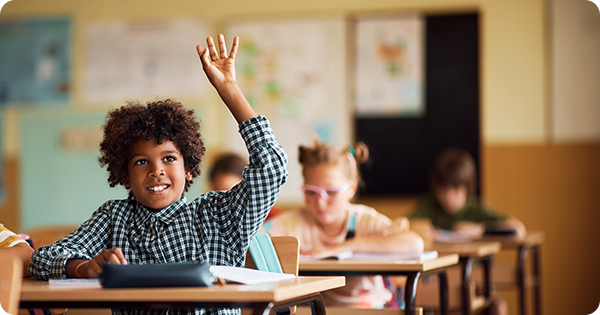 A kid raising his hand in a classroom