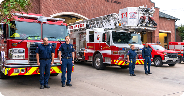 Waco firefighters standing in front of fire engines at Fire Station Number 1.