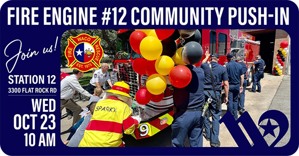Kids, firefighters, and Sparky the fire dog mascot pushing a fire engine decorated in balloons.