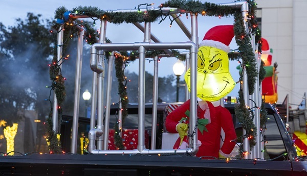 A truck with Christmas lights and the Christmas Grinch behind bars