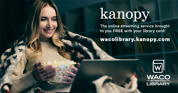 A woman with blankets and a bowl of popcorn watching a movie on her laptop