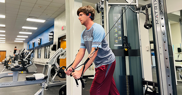 A man exercising with a wire pull machine