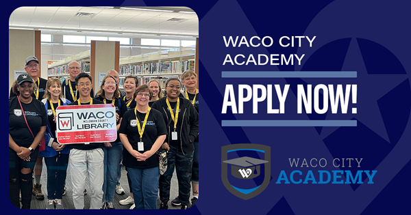A group of people holding an oversized library card in a library