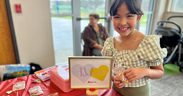 A young girl displaying her artwork for sale