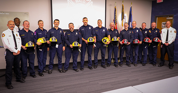 Group of Waco firefighters. Some holding yellow firefighter hats others red.