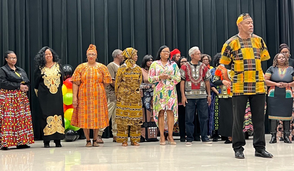 A group of Black men and women on the stage. Some dressed in traditional African clothing.