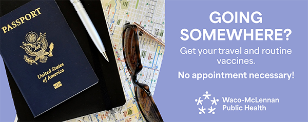 A passport, iPad, map, and sunglasses lay on a table