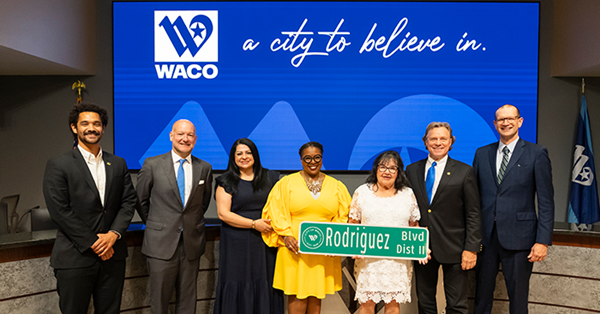 Alice Rodriguez with fellow councilmembers holding her personalized City street sign