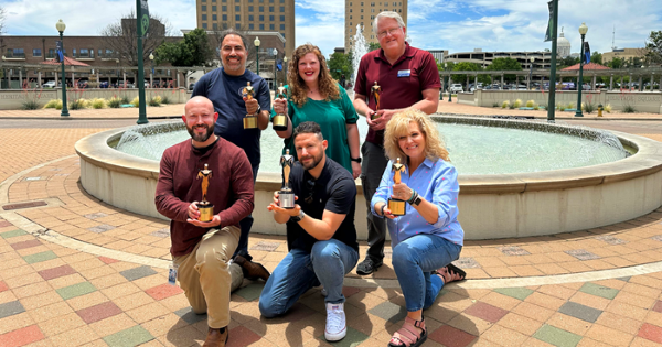 City staff, four men and two women, holding their trophies in front of a fountain