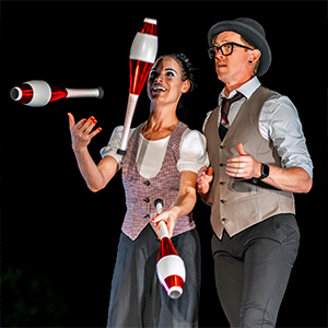 A man and a woman juggling bowling pins