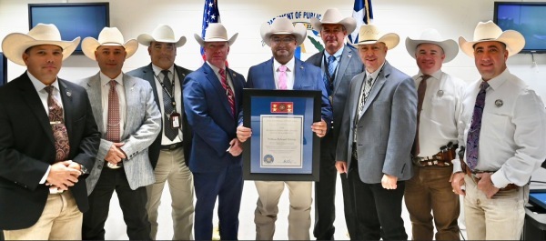Ranger Groves holds framed award surrounded by Rangers in white cowboy hats