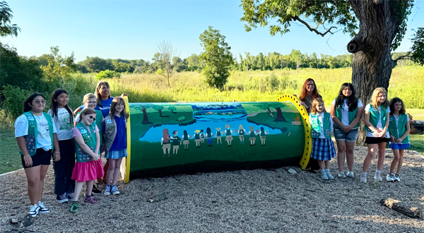 Girl Scouts standing next to painted playground tunnel