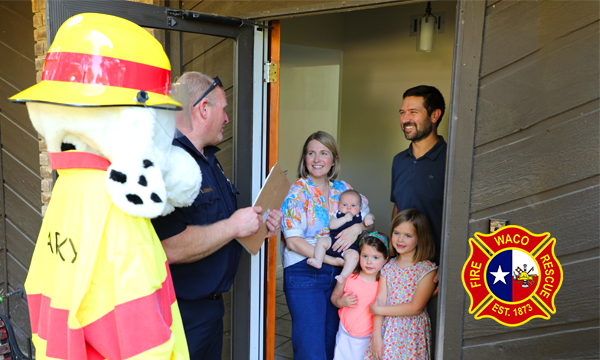 A family with a mom, dad, two girls, a baby boy greeting a firefighter and Sparky the Dog